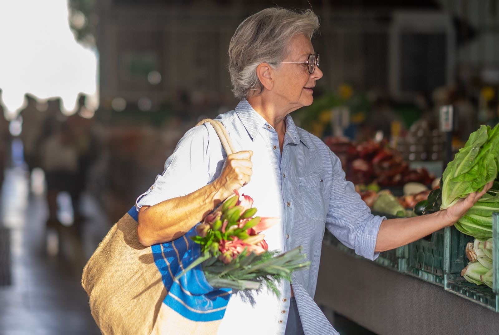 A woman in her sixties choosing vegetables at a market